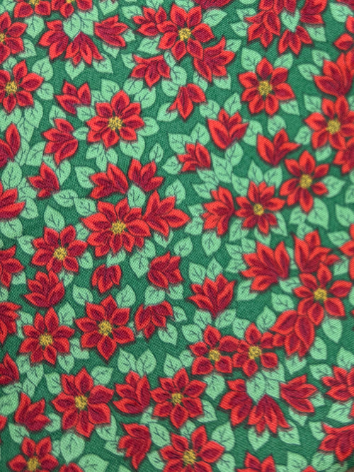 Green fabric with red floral pattern on a wooden surface