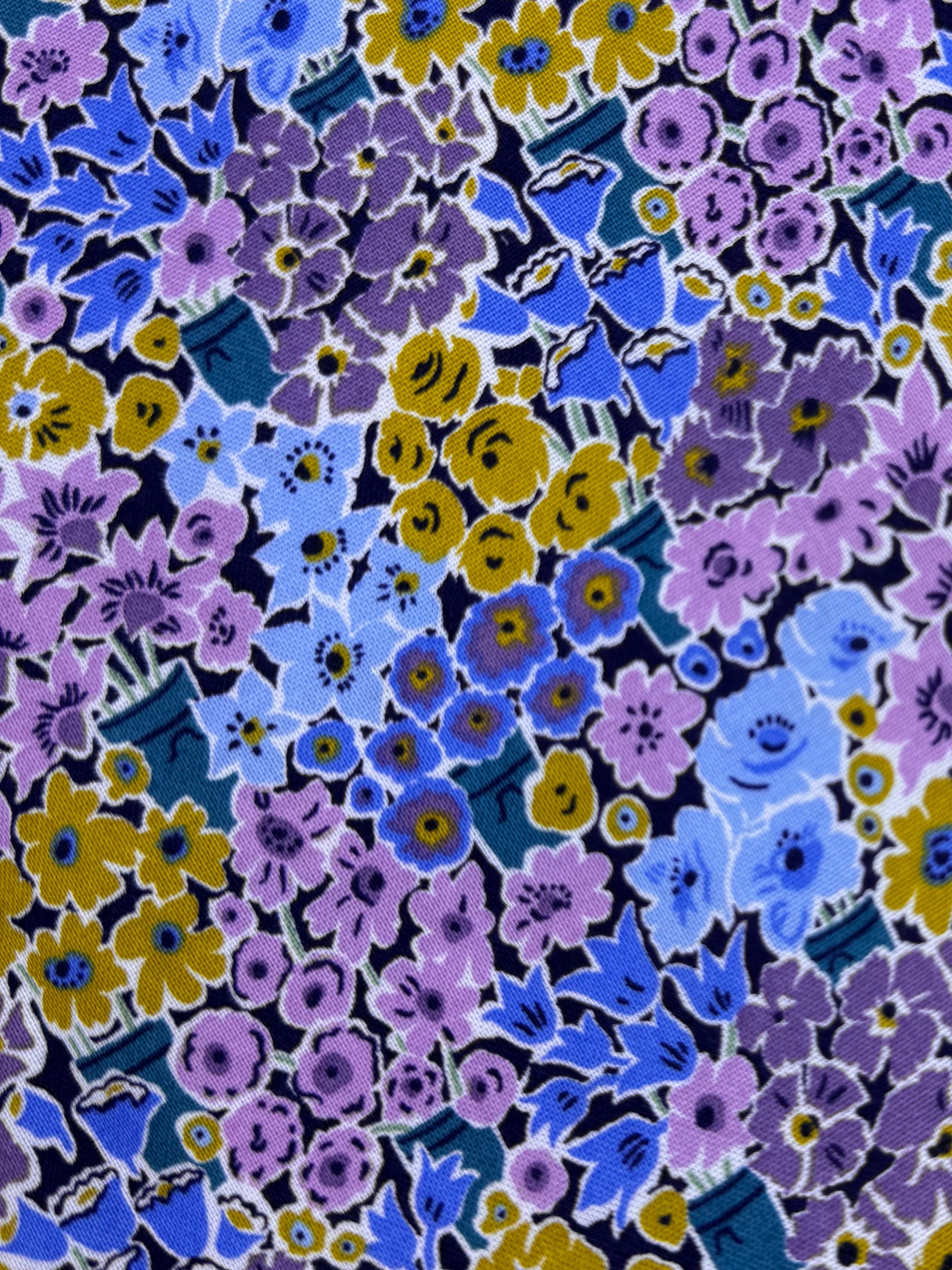 Floral fabric with purple, blue, and yellow flowers on a wooden surface