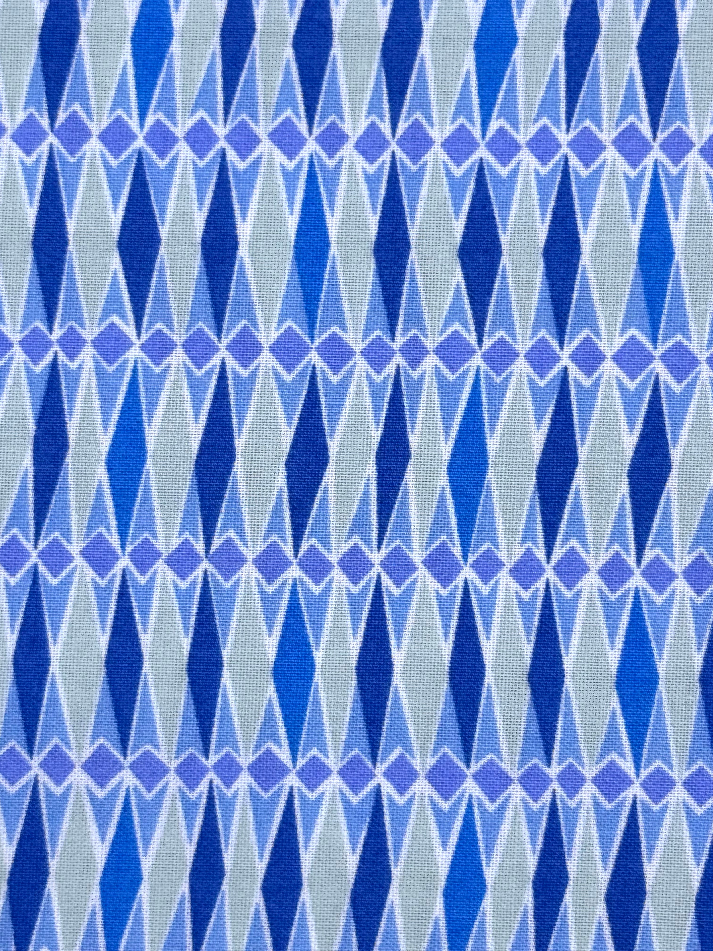 A close-up of a woven fabric with a repeating geometric pattern of blue and purple diamonds on a light gray background.
