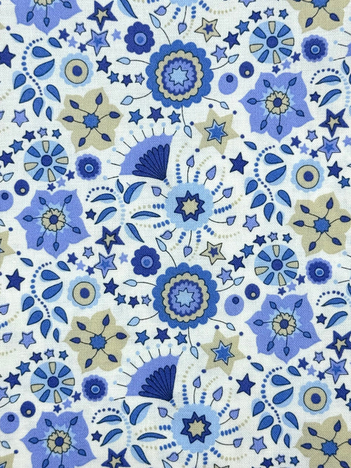 A close-up of a fabric or wallpaper pattern featuring a dense, repeating design of blue and navy floral motifs, stars, and abstract shapes on a white background.