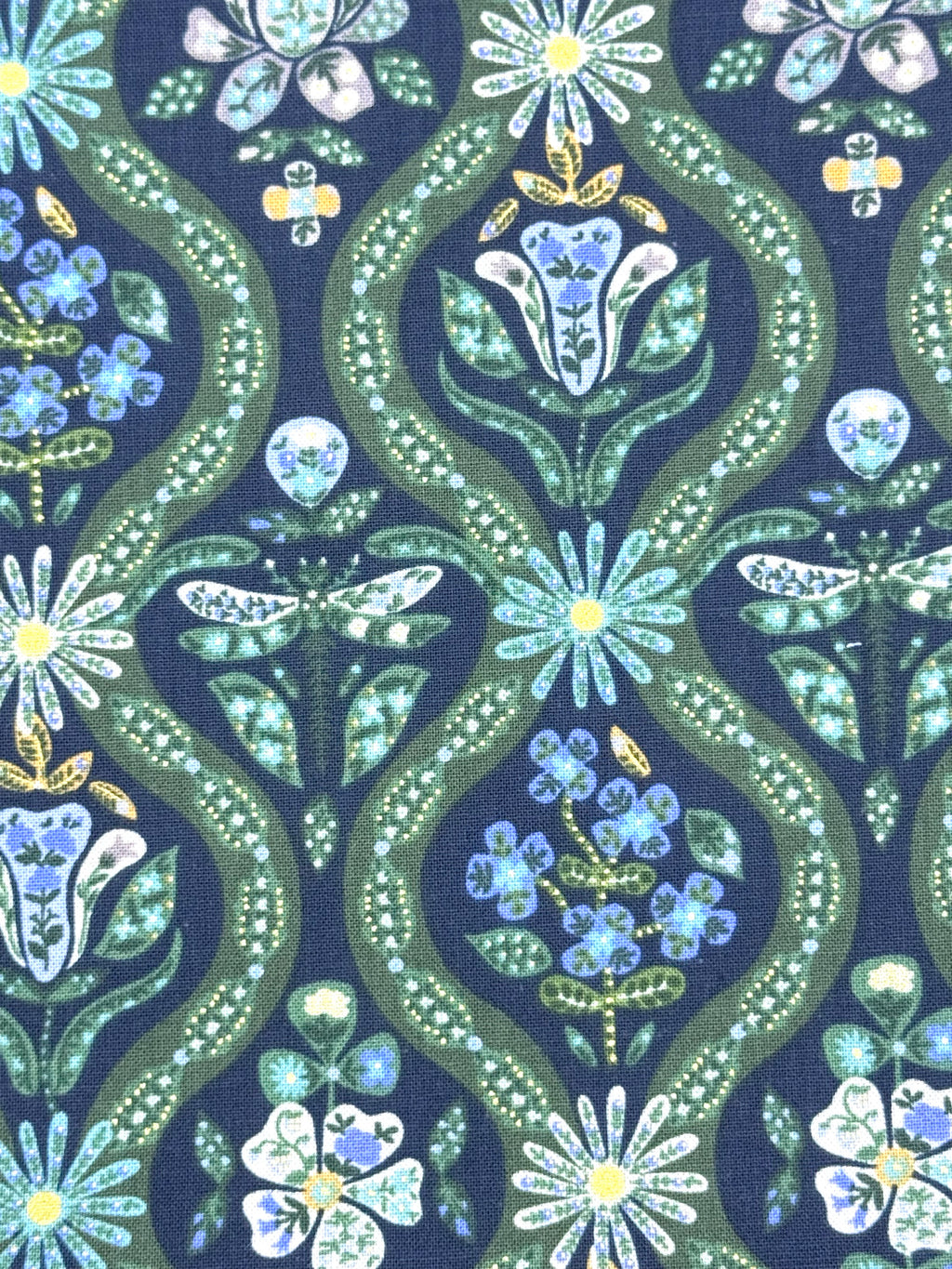 A close-up of a fabric pattern featuring a dark black background with repeating vertical wavy bands in olive green, decorated with stylized flowers, leaves, and small insects in light blue, white, and yellow.