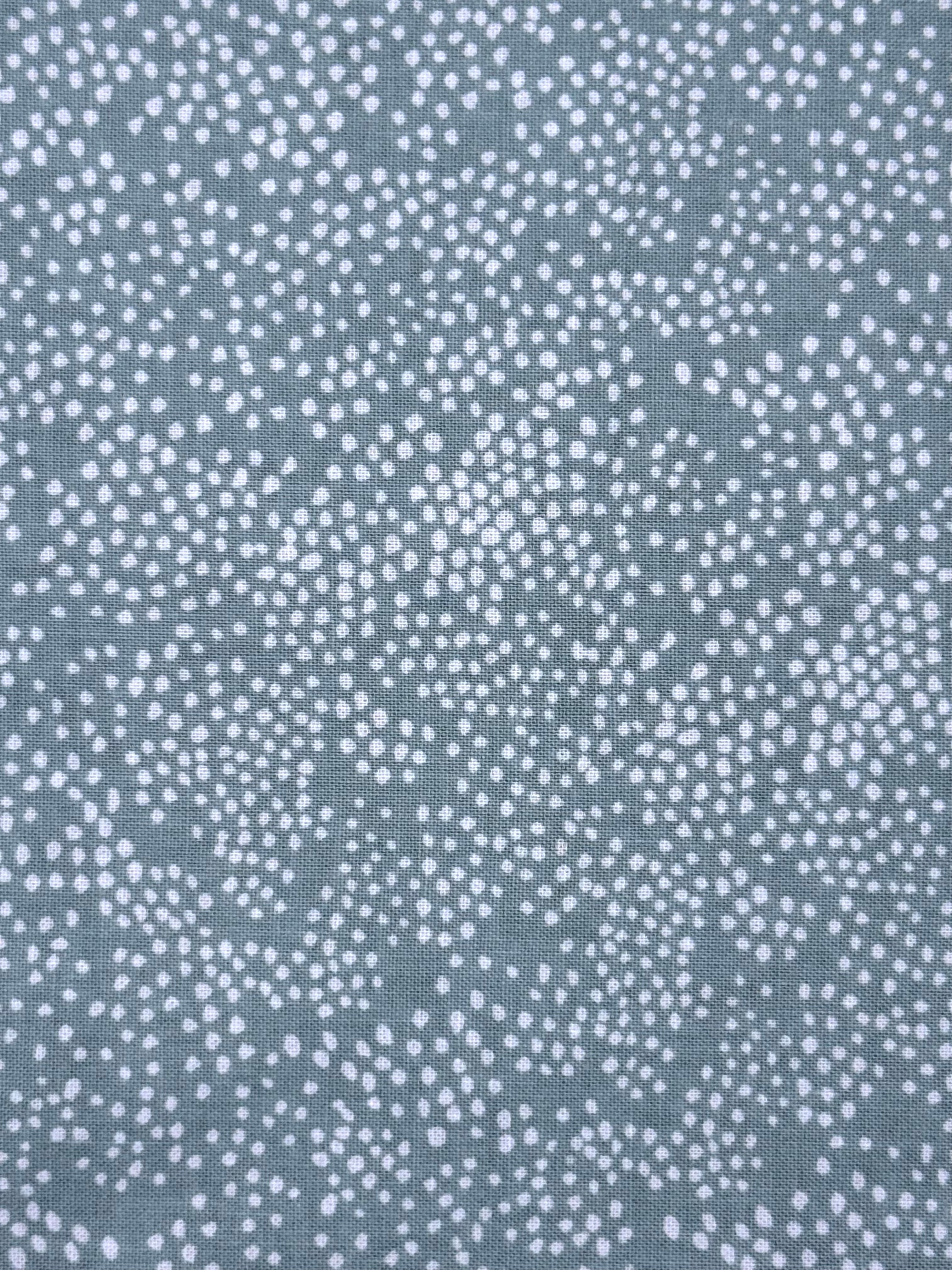 A close-up of a fabric or material swatch with a repeating white dotted pattern on a muted blue-sage background.