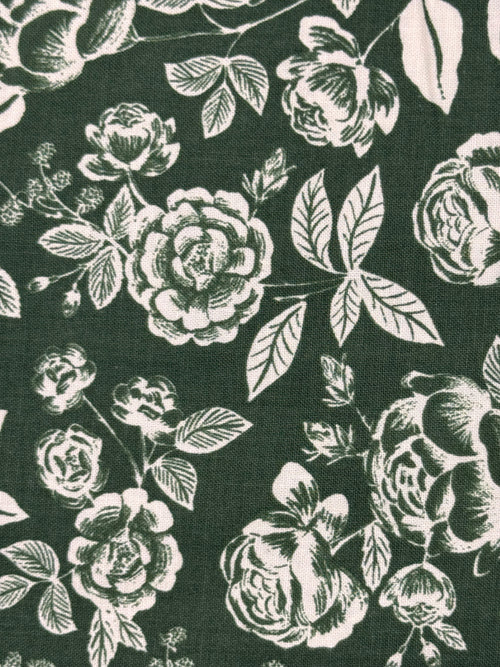 Dark forest green fabric with a white floral rose pattern, showing a close-up of the woven textile texture.