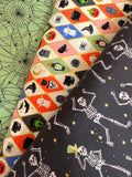 Halloween-themed fabric with skeletons, ghosts, and pumpkins on a black background.
