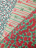 Three Christmas-themed patterned fabrics arranged diagonally, featuring a holly and berry print, a striped design with bows, and a red poinsettia floral pattern on green.